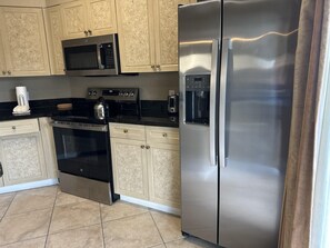 A kitchen with a stainless steel refrigerator, a microwave, an oven, and a coffee maker. - 3402 Spacious 3/2 Resort Condo Near Disney (Orlando)