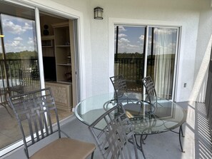A glass-top table with four chairs on a balcony with a view. - 3402 Spacious 3/2 Resort Condo Near Disney (Orlando)