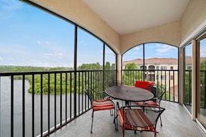 A balcony with a table and chairs, overlooking a body of water and a residential area. - 3502 Spacious 3/2 Resort Condo Near Disney (Orlando)