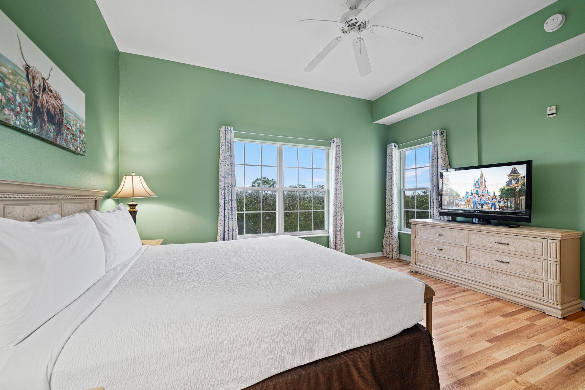Quarto com cama, cômoda, televisão e janela.