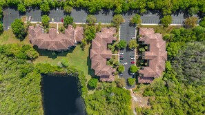 An aerial view of a residential area with multiple houses, a parking lot, and a body of water.