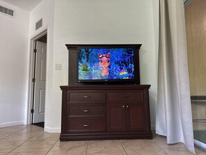 A television on a dark wooden cabinet with a tiled floor.