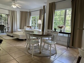Un coin repas avec une table ronde, des chaises blanches et un ventilateur de plafond.