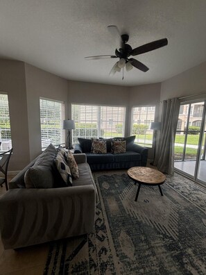 Ein Wohnzimmer mit einer Couch, einem Couchtisch und einem Deckenventilator.