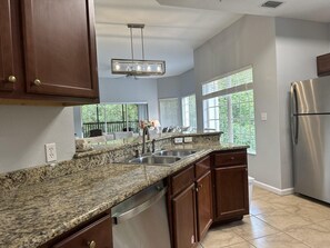 A modern kitchen with granite countertops, stainless steel appliances, and a large window providing natural light. - 4201 Spacious 3/2 Resort Condo Near Disney (Orlando)