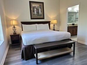 A neatly made bed with a headboard, two bedside tables with lamps, a bench at the foot of the bed, and a framed picture above the bed. - 4307 Spacious 3/2 Resort Condo Near Disney (Orlando)