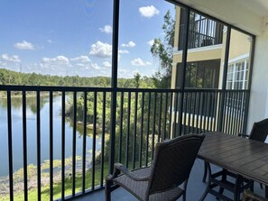 A balcony with a view of a lake, a dining table, and chairs. - 4307 Spacious 3/2 Resort Condo Near Disney (Orlando)