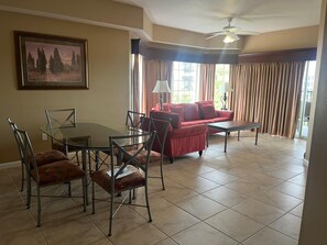 A spacious living area with a dining table, chairs, a red sofa, and a ceiling fan. - 4407 Spacious 3/2 Resort Condo Near Disney (Orlando)