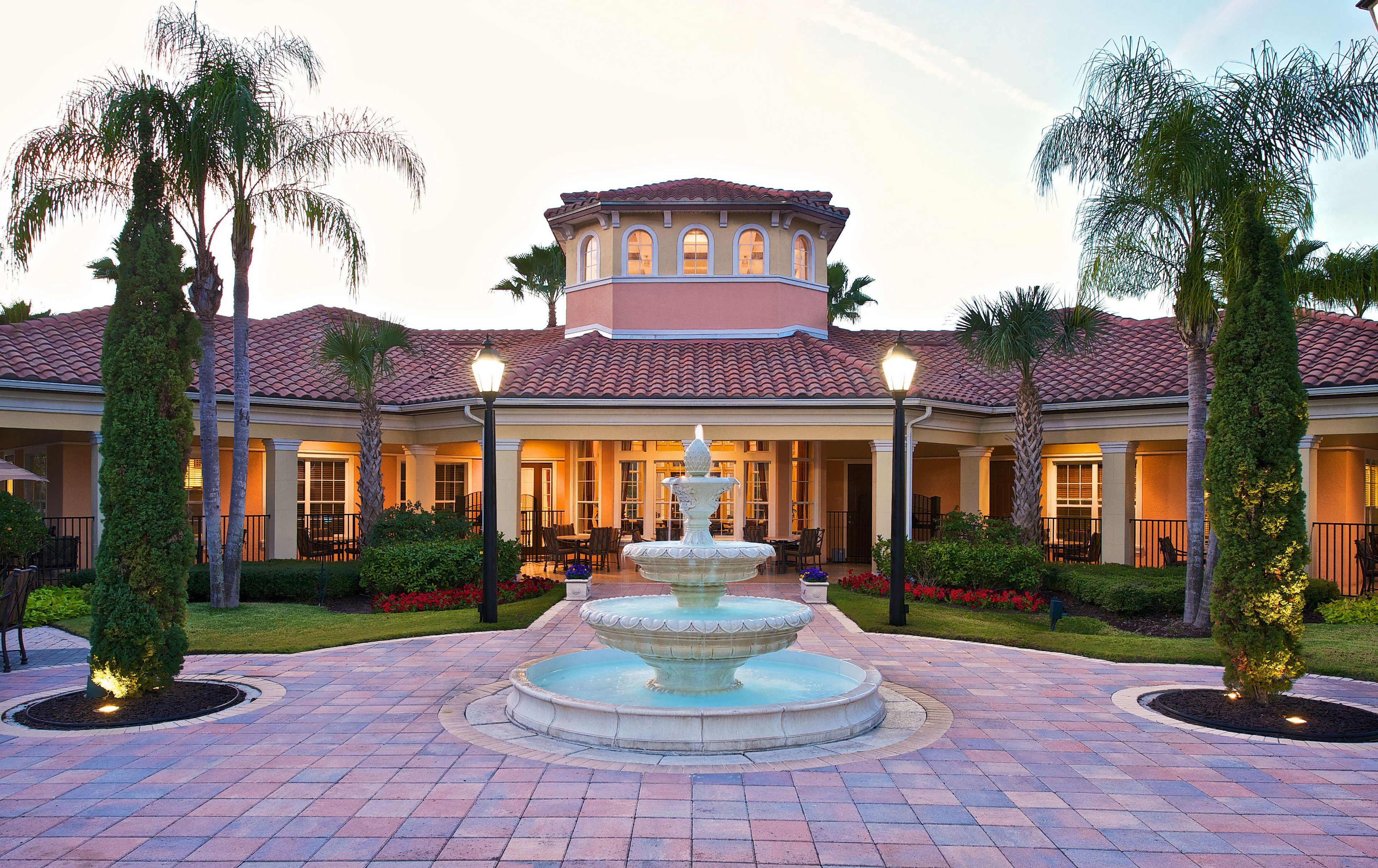 A hotel with a central fountain, outdoor seating, and a well-maintained garden.