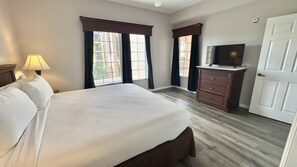 A hotel room with a bed, a TV on a dresser, and a door. - 5302 Spacious 3/2 Resort Condo Near Disney (Orlando)