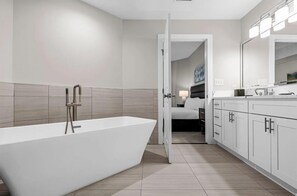 A modern bathroom with a freestanding bathtub, a large mirror, and a walk-in shower.