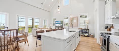 Una cocina amplia con una isla grande, muebles blancos y un diseño moderno.
