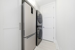 Uma cozinha compacta equipada com frigorífico, máquina de lavar e uma porta.