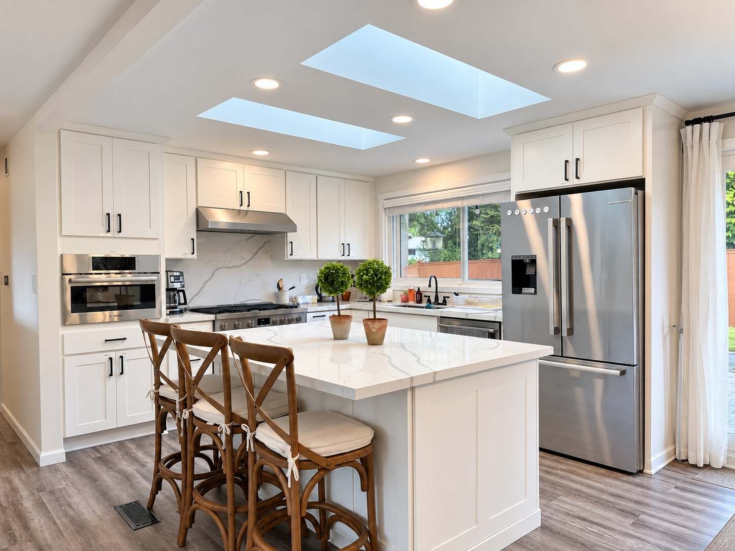 A modern kitchen with white cabinetry, a central island, and a stainless steel refrigerator.