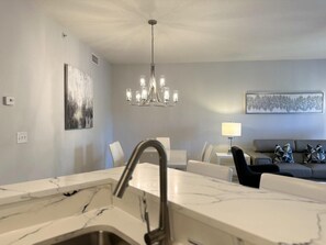 A modern kitchen with a marble countertop and a stainless steel sink.
