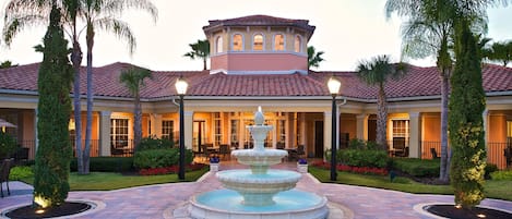 Un hotel con una fuente central, mobiliario exterior y un jardín cuidado.