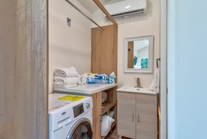 A compact bathroom with a washing machine, a sink, and a mirror. - Glamping Pods at Tiffany's Estate | Hot Tub, Fire Pit, Pickleball, & Pond (Elk Park)