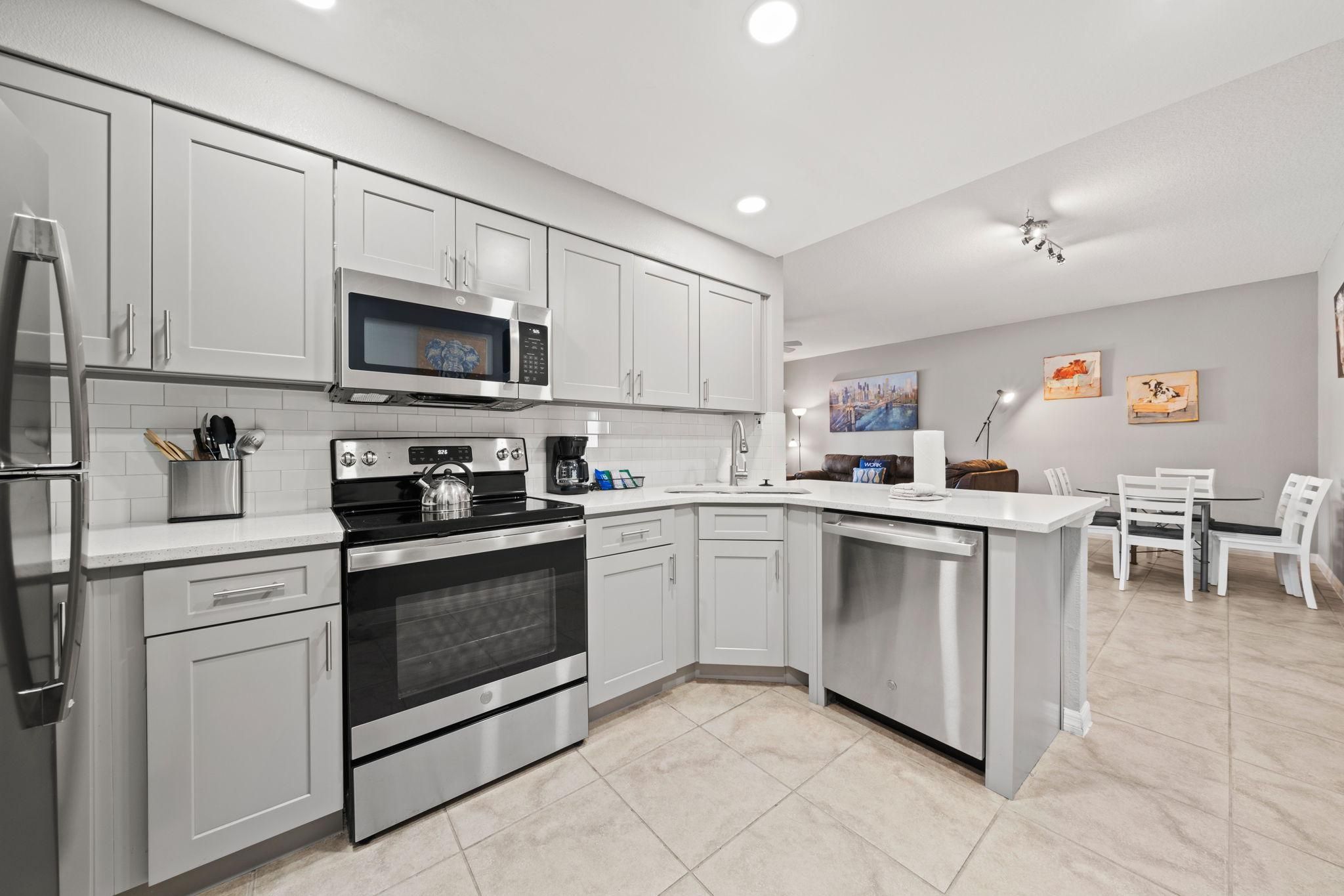 A modern kitchen with stainless steel appliances, white cabinetry, and a dining area with a white table and chairs.