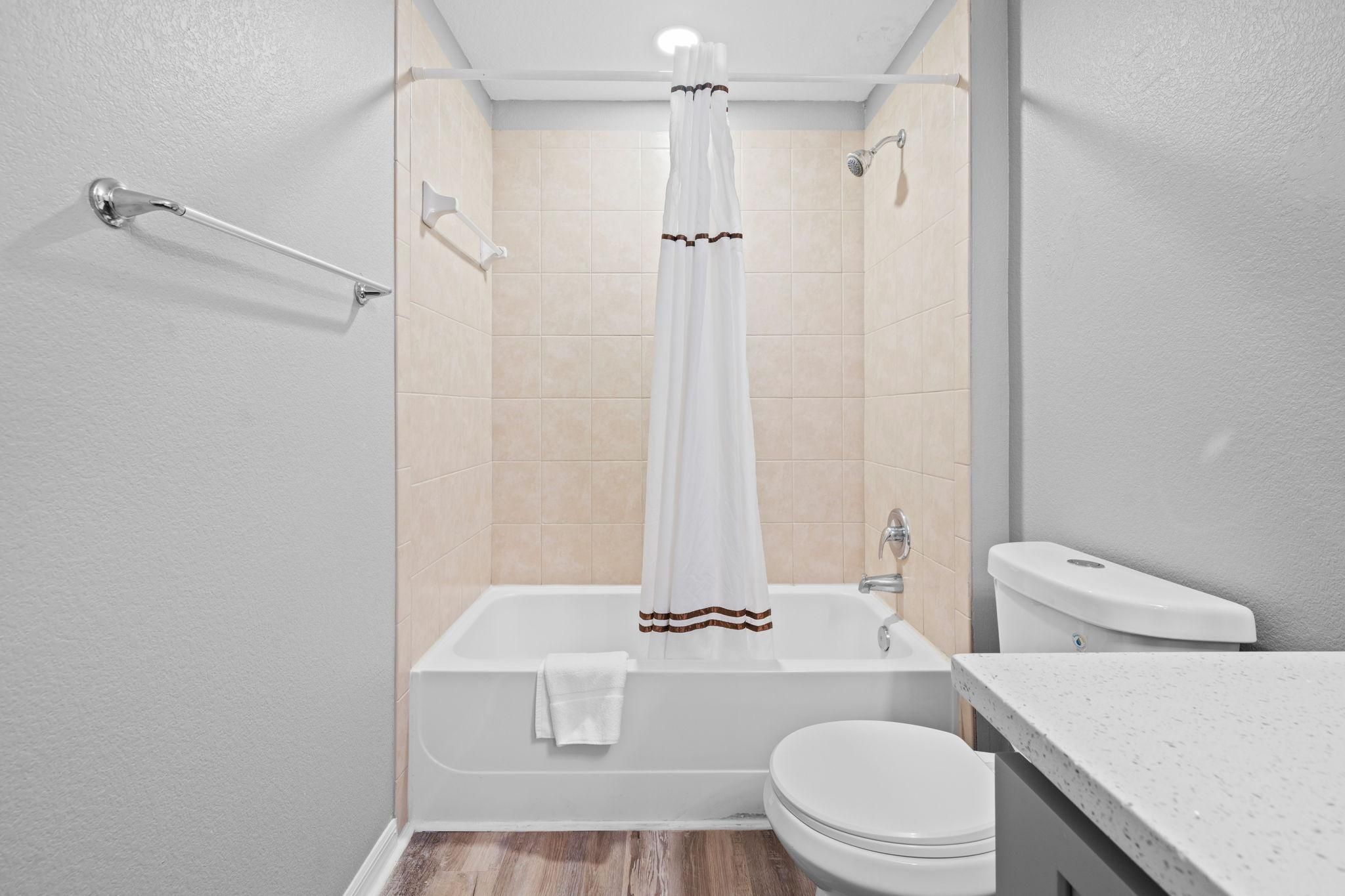 Et moderne badeværelse med badekar, toilet og bruseniche.
