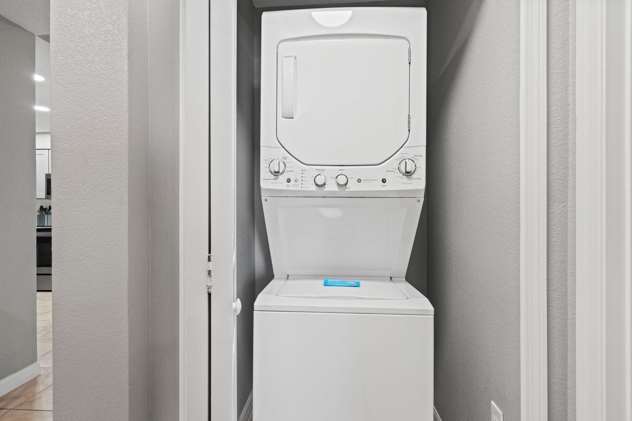 A compact, white, wall-mounted washer and dryer unit with a control panel featuring multiple settings.