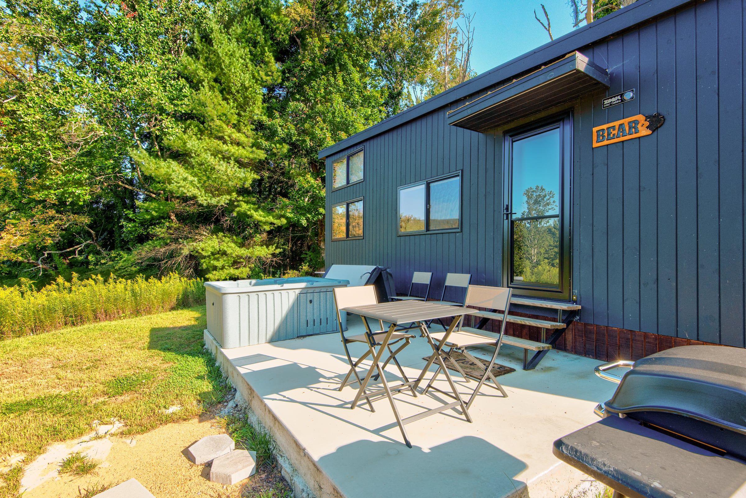 A modern cabin with a pool, outdoor seating, and a sign indicating 'BEAR'.