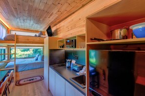 A compact cabin with a bunk bed, kitchenette, and a view of the forest. - Bear Pod at Tiffany's Estate | Hot Tub, Fire Pit, Pickleball, & Pond (Elk Park)