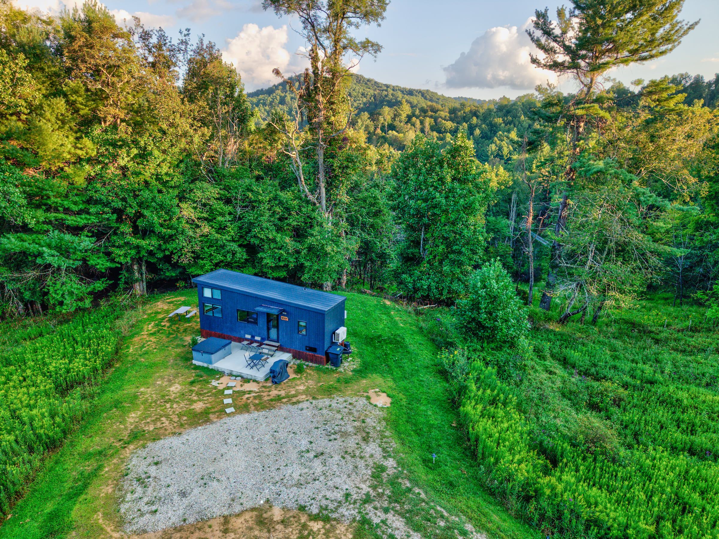 A small, single-story cabin with a gravel driveway and a patio area.