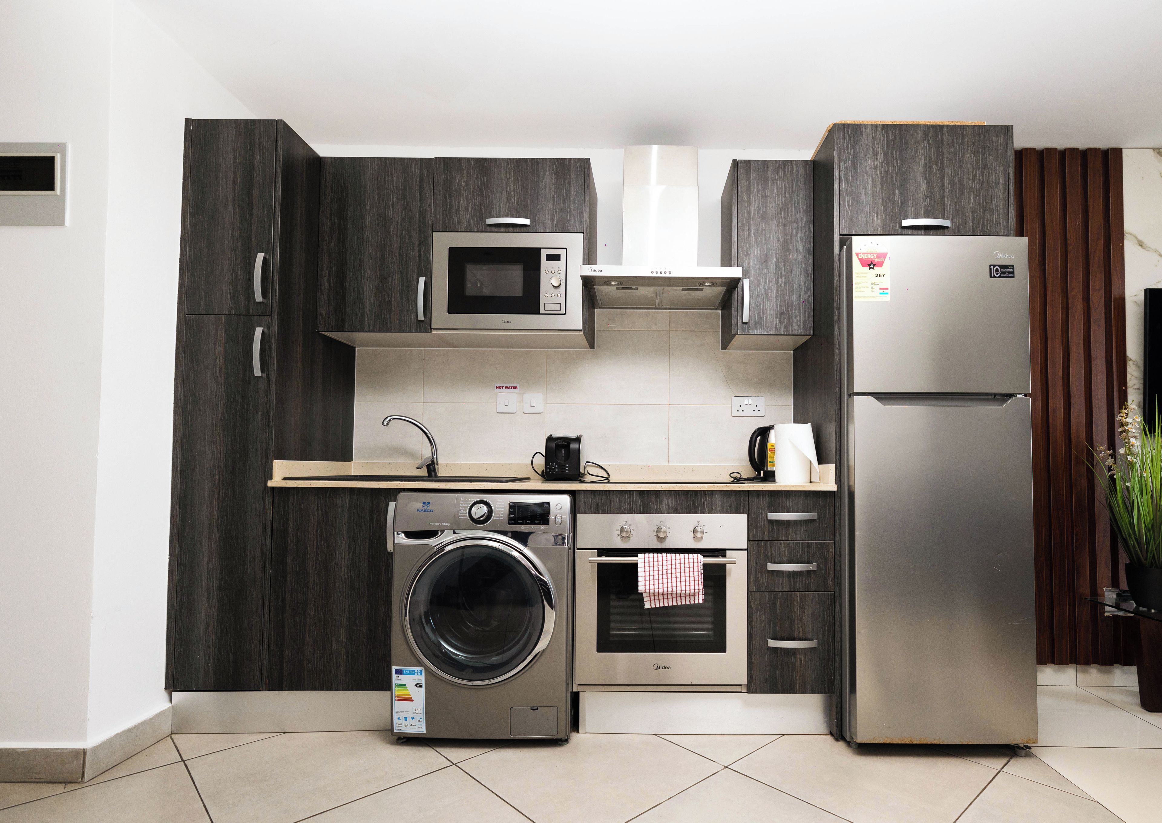 Una cocina moderna con lavadora integrada, horno, microondas y refrigerador.