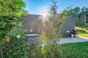 Eine Terrasse mit Grill, Sitzgelegenheit und einer großen Wasserspielfläche.