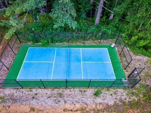 Ein Tennisplatz im Freien, umgeben von dichtem Wald.