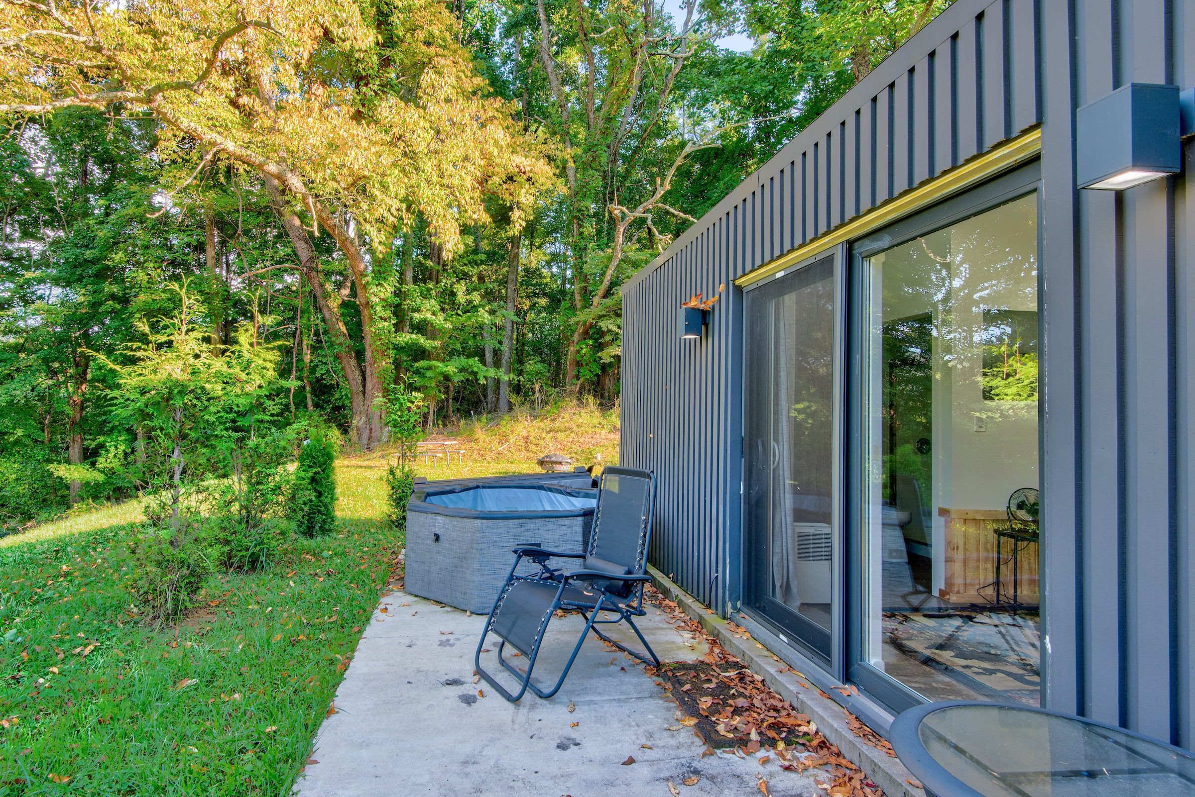 A modern building with a glass door and a small outdoor seating area with a chair and a table.
