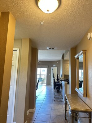 A hallway with a bench, a door, and a view to a balcony. - 1405 Spacious 3/3 Resort Condo Near Disney (Orlando)