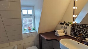 Casa de banho moderna com uma janela grande, toucador com espelho e banheira.