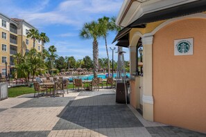 Ein Poolbereich eines Resorts mit Liegestühlen, Sonnenschirmen, einem Pool und einem Starbucks-Schild.