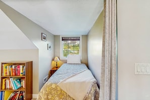 Ein Schlafzimmer mit einem Bett, einem Fenster, einem Bücherregal und einer Lampe.