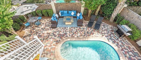 Un espace piscine comprenant un jacuzzi, des sièges et un barbecue.