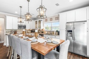 A modern kitchen with white cabinets, stainless steel appliances, and a wooden island with chairs.