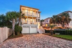 A two-story house with a front garage, a brick driveway, and a wooden fence.