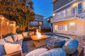 A poolside area with a fire pit, outdoor seating, and a building with a balcony.