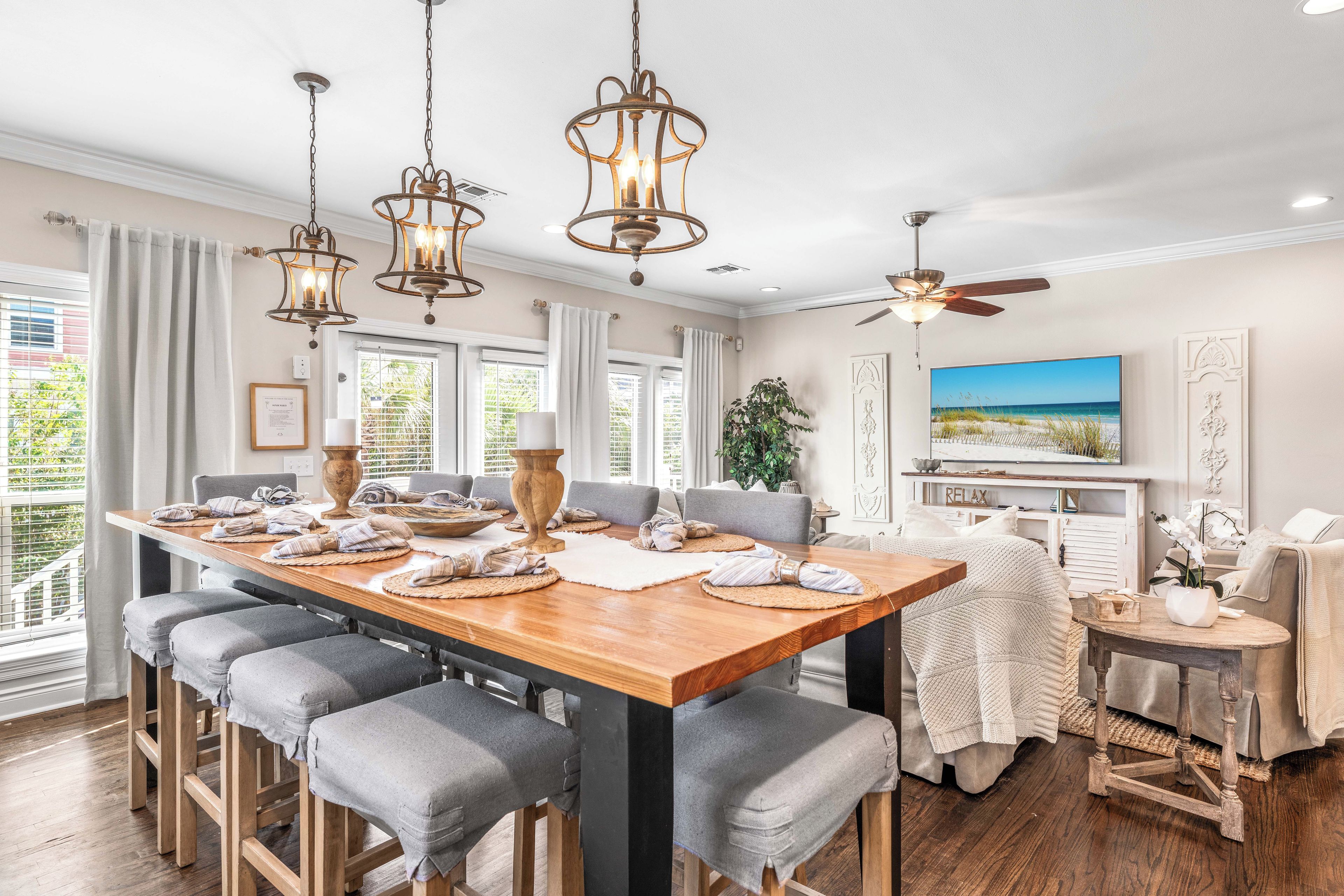 A spacious dining area with a wooden table, grey upholstered chairs, and pendant lighting.