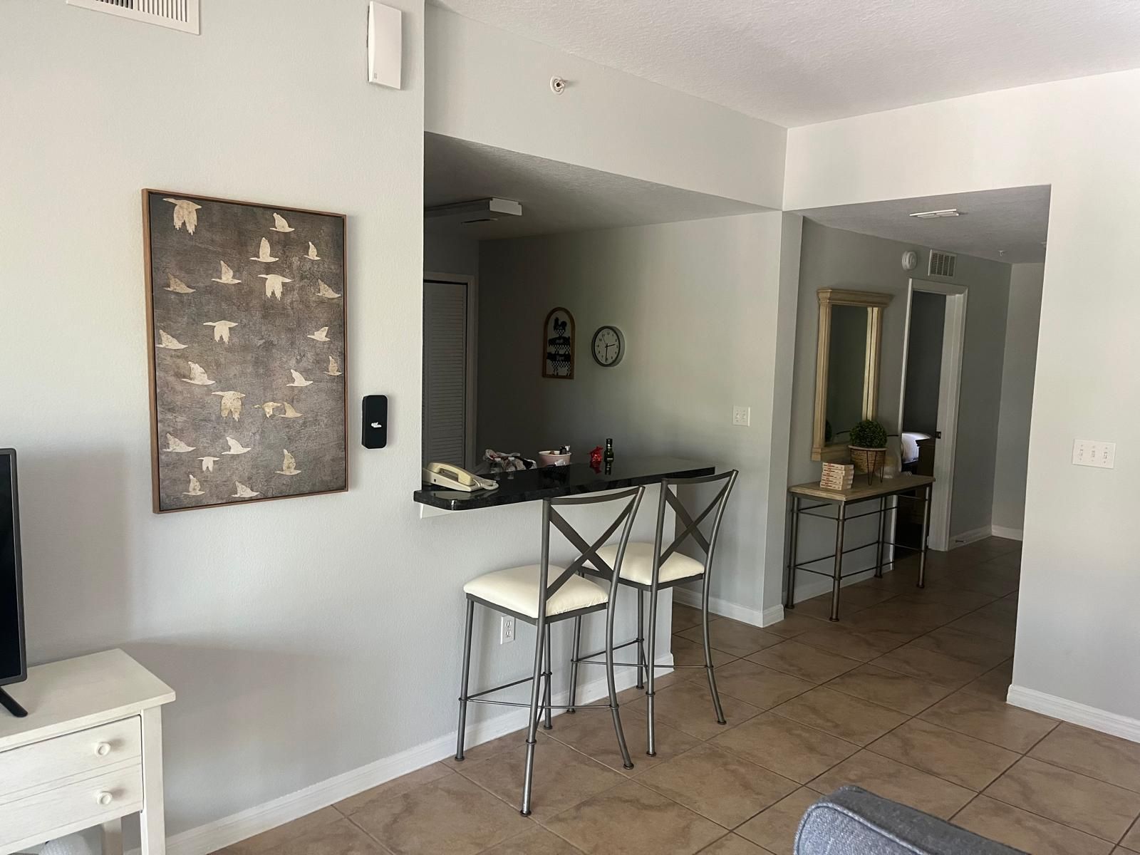 A modern kitchen with a central island, bar stools, and a dining area.
