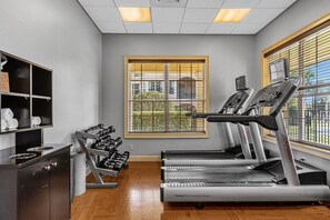 A gym with treadmills, dumbbells, and a window with blinds. - 2404 3B/3 Home Away From Home Near Disney (Orlando)