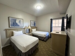 A hotel room with two beds, a desk, a television, and artwork on the walls. - 2405 Spacious 3/3 Resort Condo Near Disney (Orlando)