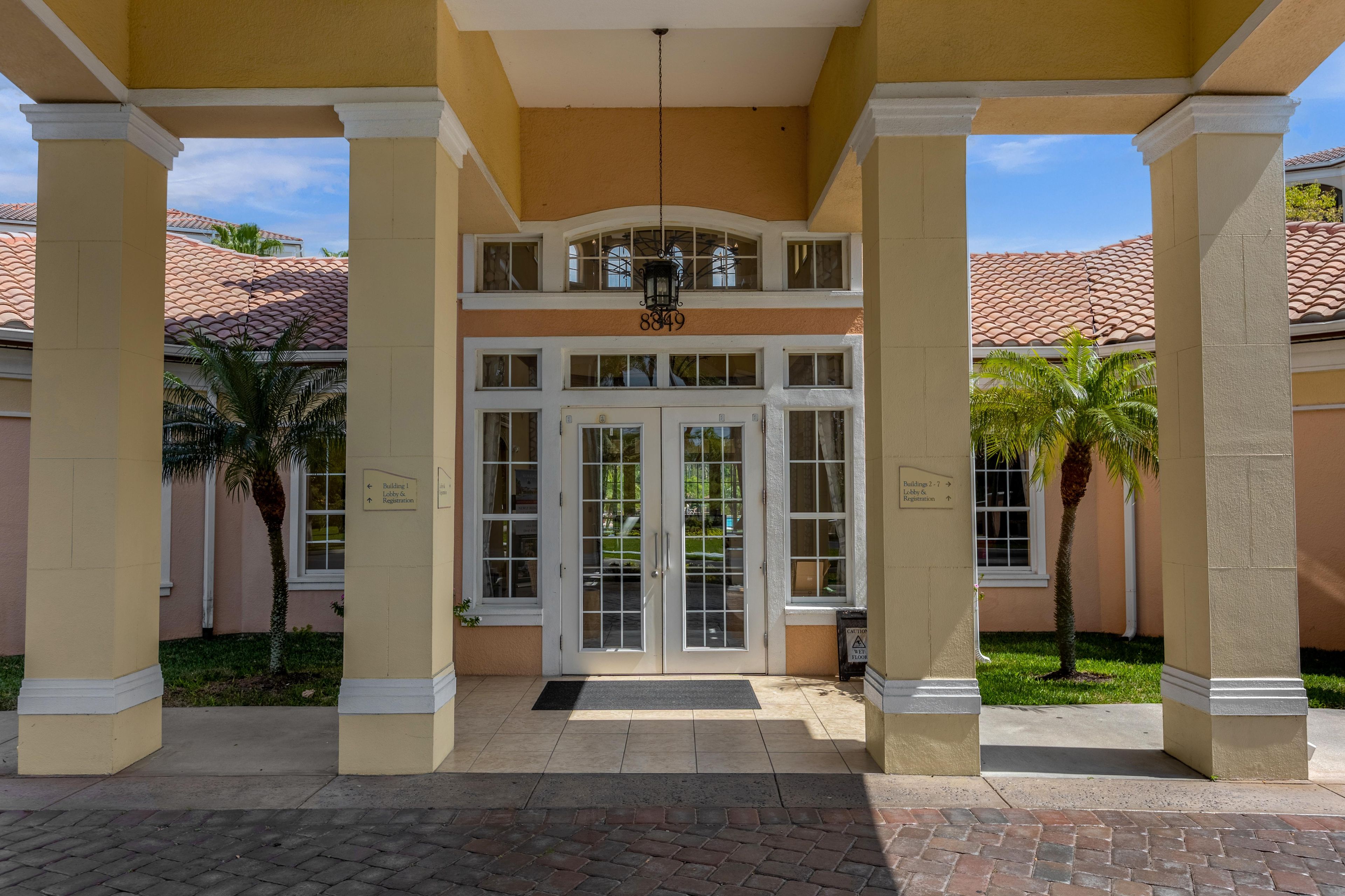A building entrance with a double door, columns, and a sign indicating the lobby and registration.