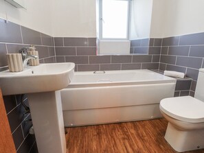 A bathroom with a bathtub, sink, and toilet. - Hen Blas (Pwllheli)