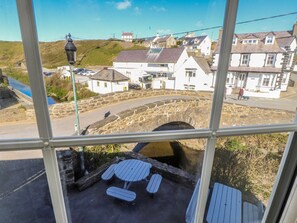 A stone bridge over a river, white buildings, and a table with benches in the foreground. - Hen Blas (Pwllheli)