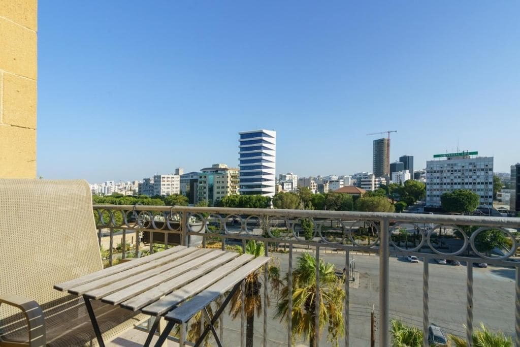 A balcony with a view of a cityscape, including buildings and palm trees.