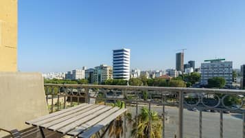 A balcony with a view of a cityscape, including buildings and palm trees.