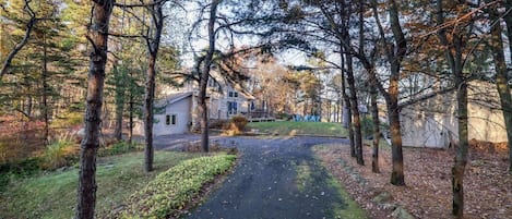 Ett bostadsområde med en asfalterad uppfart som leder fram till ett hus omgivet av träd.