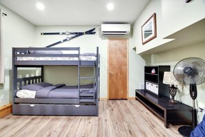 A bunk bed with a ladder, a wooden door, a desk with a lamp, and a wall-mounted air conditioner. - 🌊 Lakefront Poconos Retreat | Private Beach • Kayaks • Fire Pits (Long Pond)